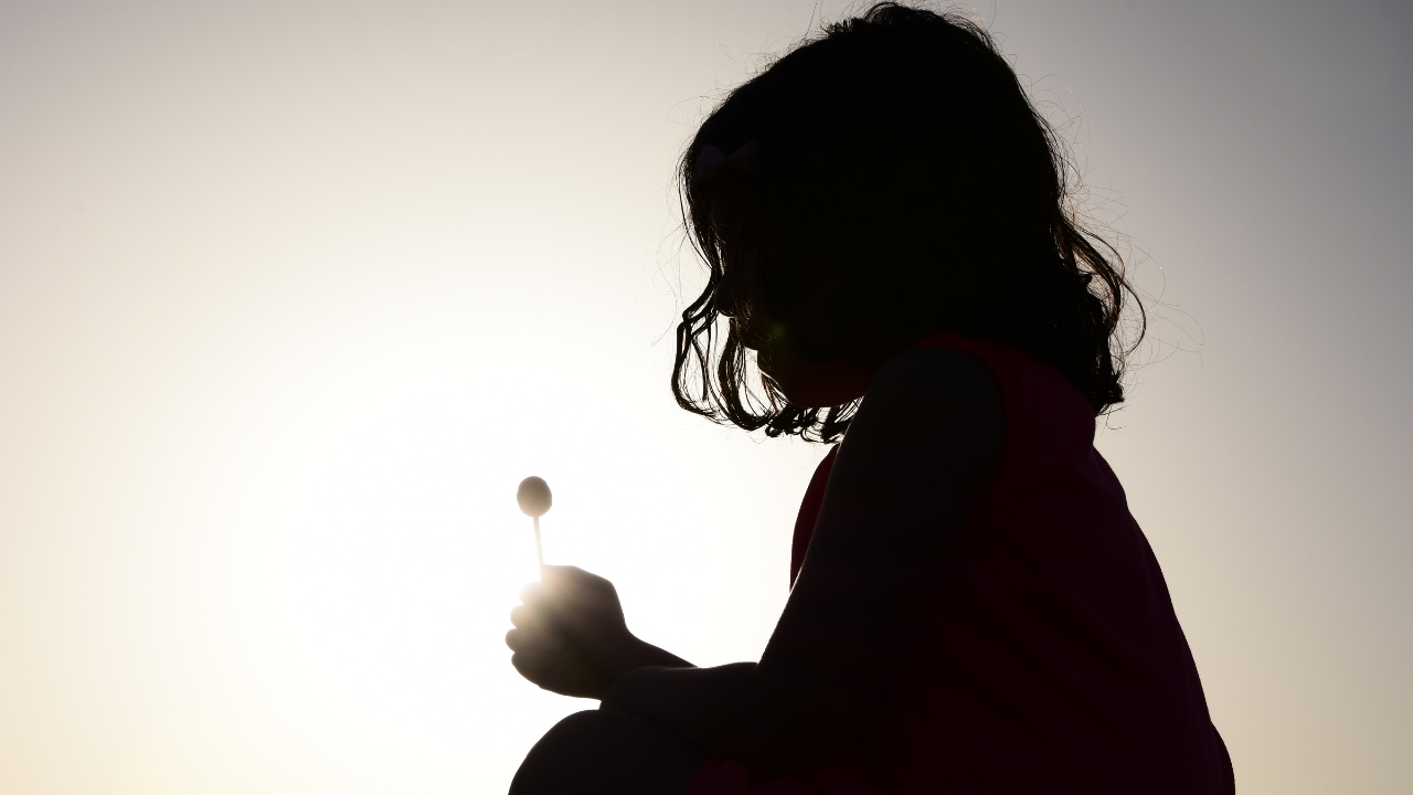 A child in silhouette holding a flower