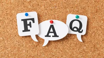 The letters FAQ pinned to a cork board.