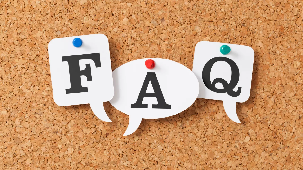 The letters FAQ pinned to a cork board.