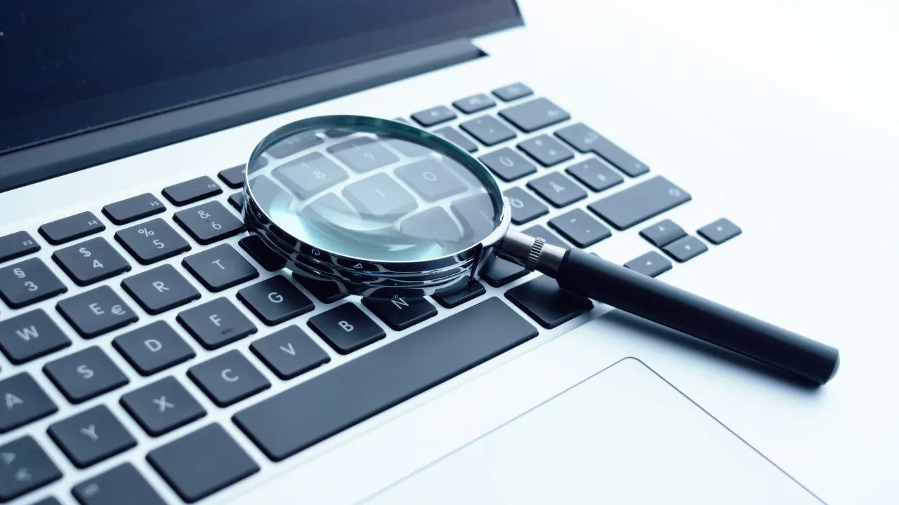 image of a magnifying glass on a laptop to signify scrutiny of data