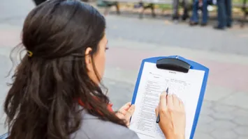Generic image of a woman with a clipboard doing a survey.
